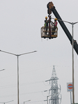 Electrician Working on an Electric Lamp Post on a Cloudy Day in West Bengal