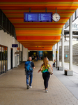 Travelers Beneath The Timetable At A Germann Train Station