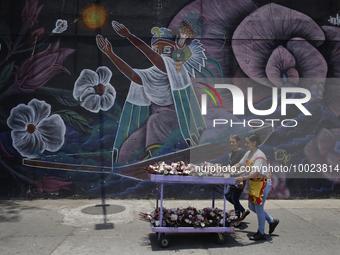 Two people carry flowers outside the Jamaica Market in Mexico City where dozens of people came to buy flowers and gifts for Mother's Day, wh...