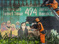 Municipal worker removed a mural promoting awareness of the coronavirus disease (Covid-19) and replaced it with another image in Jakarta, In...