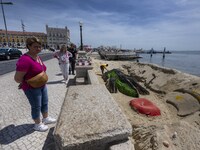 Several people are seen looking at sculptures on the riverbank near a beach on the Tejo river, in the Baixa neighborhood, Lisbon. 02 May 202...