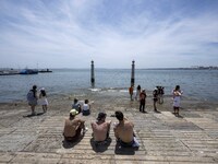 Several people are seen resting on the banks of the Tejo river, in the neighborhood of Baixa, Lisbon. 02 May 2023. (