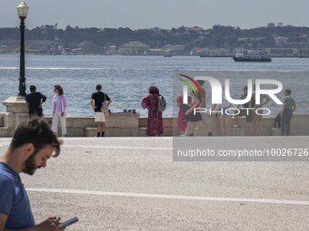 Several people are seen resting on the banks of the Tejo river, in the neighborhood of Baixa, Lisbon. 02 May 2023. (