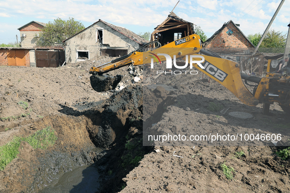 ZOLOCHIV, UKRAINE - MAY 14, 2023 - An excavator digs the ground after the rocket attack by Russia that, allegedly, used S-300 surface-to-air...