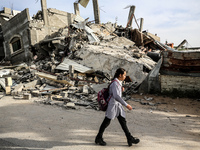 A Palestinian student walks past amidst the rubble of his house in Beit Lahia in the northern Gaza Strip, on May 16, 2023, following a cease...