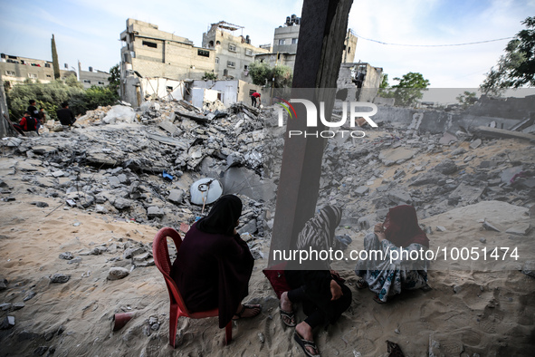 Palestinians inspect their belongings amidst the rubble of their house in Beit Lahia in the northern Gaza Strip, on May 16, 2023, following...