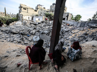 Palestinians inspect their belongings amidst the rubble of their house in Beit Lahia in the northern Gaza Strip, on May 16, 2023, following...