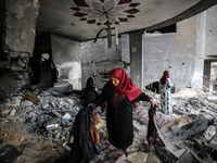 Palestinians inspect their belongings amidst the rubble of their house in Beit Lahia in the northern Gaza Strip, on May 16, 2023, following...