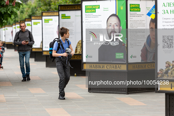 People walk on an alee by posters dedicated to fallen soldiers in Bucha, Ukraine on May 17, 2023. The poster are singed 'Glory to the heroes...