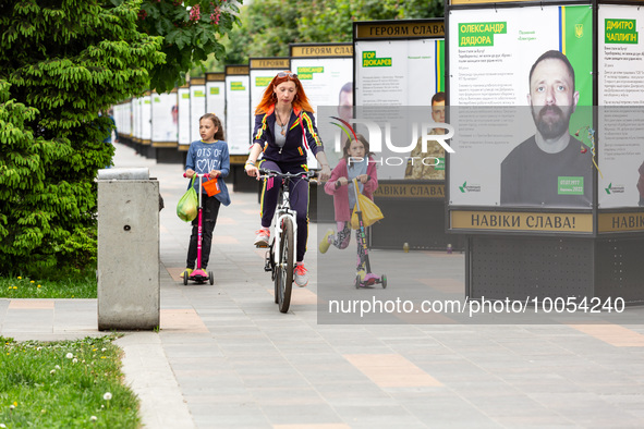 People walk on an alee by posters dedicated to fallen soldiers in Bucha, Ukraine on May 17, 2023. The poster are singed 'Glory to the heroes...