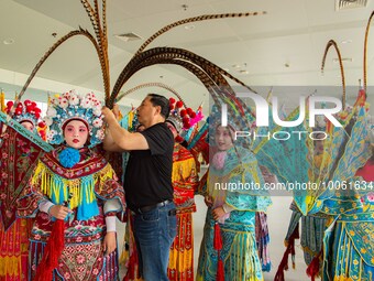  A Peking Opera teacher dresses students in costumes at a primary school Peking Opera club in Hai 'an, East China's Jiangsu province, May 20...