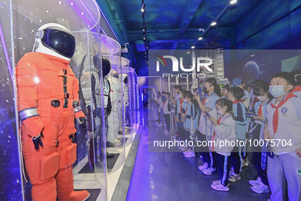 QINGZHOU, CHINA - MAY 23, 2023 - Primary school students watch and take photos of a space suit model at the Artificial Intelligence Learning...