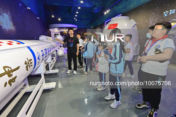 QINGZHOU, CHINA - MAY 23, 2023 - Primary school students listen to a staff member explain aerospace science and technology at an artificial...