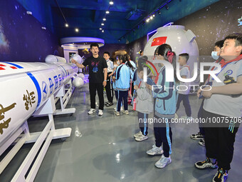 QINGZHOU, CHINA - MAY 23, 2023 - Primary school students listen to a staff member explain aerospace science and technology at an artificial...