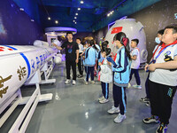 QINGZHOU, CHINA - MAY 23, 2023 - Primary school students listen to a staff member explain aerospace science and technology at an artificial...