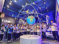 QINGZHOU, CHINA - MAY 23, 2023 - Primary school students listen to a staff member explain Beidou navigation knowledge at the Artificial Inte...