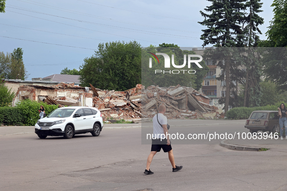 OKHTYRKA, UKRAINE - MAY 24, 2023 - A man crosses a street near a building ruined by Russian shelling, Okhtyrka, Sumy Region, northeastern Uk...