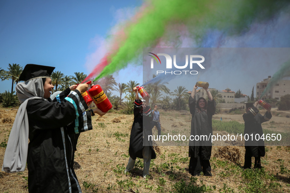 Students from the University of Palestine spray colors as they celebrate the end of the academic year in Gaza City on May 31, 2023. 