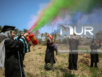 Students from the University of Palestine spray colors as they celebrate the end of the academic year in Gaza City on May 31, 2023. (