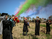 Students from the University of Palestine spray colors as they celebrate the end of the academic year in Gaza City on May 31, 2023. (