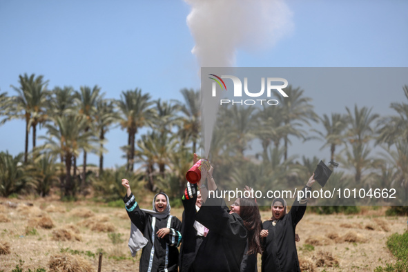 Students from the University of Palestine spray colors as they celebrate the end of the academic year in Gaza City on May 31, 2023. 