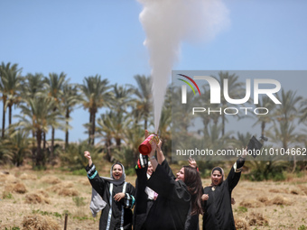 Students from the University of Palestine spray colors as they celebrate the end of the academic year in Gaza City on May 31, 2023. (