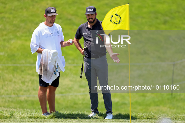 Mark Hubbard of Denver, Colorado talks with his caddie on the 18th green during the first round of the The Memorial Tournament presented by...