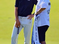 Tyrrell Hatton of High Wycombe, England talks with his caddie after putting on the 18th green during the first round of the The Memorial Tou...