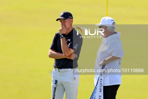 Jordan Spieth of Dallas, Texas  stands with Tyrrell Hatton’s caddie after putting on the 18th green during the first round of the The Memori...