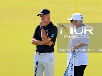 Jordan Spieth of Dallas, Texas  stands with Tyrrell Hatton’s caddie after putting on the 18th green during the first round of the The Memori...