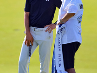 Jordan Spieth of Dallas, Texas talks with Tyrrell Hatton’s caddie after putting on the 18th green during the first round of the The Memorial...