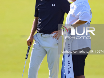 Jordan Spieth of Dallas, Texas  stands with Tyrrell Hatton’s caddie after putting on the 18th green during the first round of the The Memori...