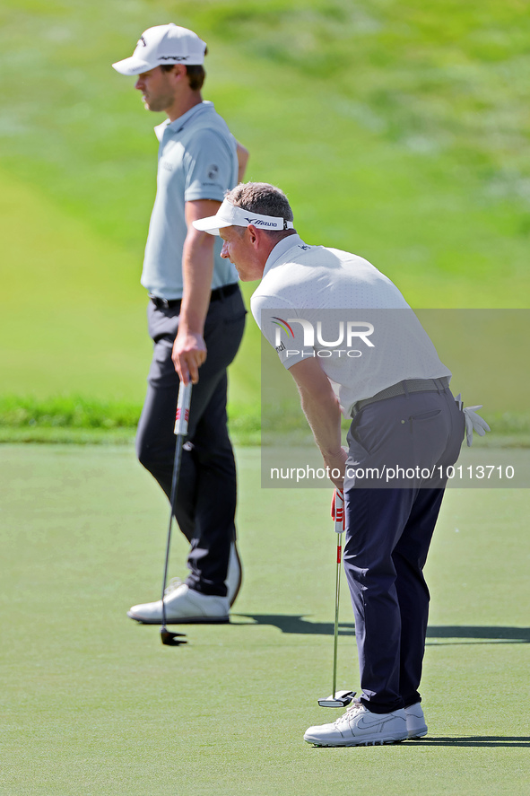 Luke Donald of England lines up his putt next to Thomas Detry of Brussels, Belgium on the 18th green during the first round of the The Memor...