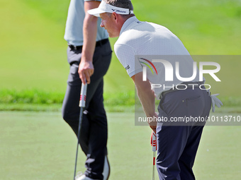 Luke Donald of England lines up his putt next to Thomas Detry of Brussels, Belgium on the 18th green during the first round of the The Memor...