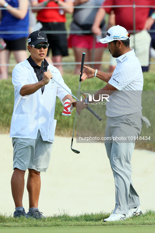 Hideki Matsuyama of Sendai, Japan exchanges clubs with his caddie on the 18th green during The Memorial Tournament presented by Workday at M...