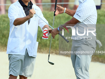 Hideki Matsuyama of Sendai, Japan exchanges clubs with his caddie on the 18th green during The Memorial Tournament presented by Workday at M...