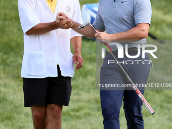 Rory McIlroy of Holywood, Northern Ireland shakes hands with his caddie on the 18th green during The Memorial Tournament presented by Workda...