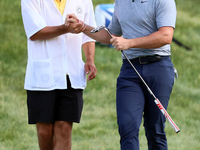 Rory McIlroy of Holywood, Northern Ireland shakes hands with his caddie on the 18th green during The Memorial Tournament presented by Workda...