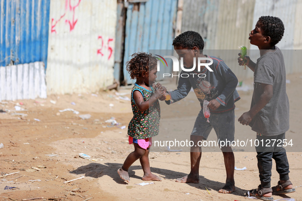 Palestinian children eat ice drinks outside their home in a poor neighborhood in Beit Lahia in the northern Gaza Strip, on June 5, 2023.  