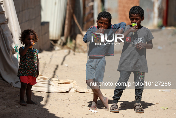 Palestinian children eat ice drinks outside their home in a poor neighborhood in Beit Lahia in the northern Gaza Strip, on June 5, 2023.  