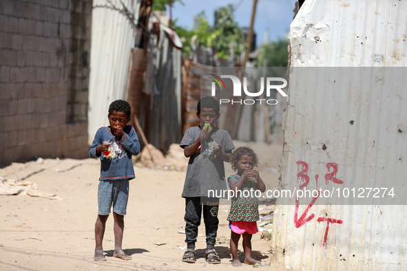 Palestinian children eat ice drinks outside their home in a poor neighborhood in Beit Lahia in the northern Gaza Strip, on June 5, 2023.  