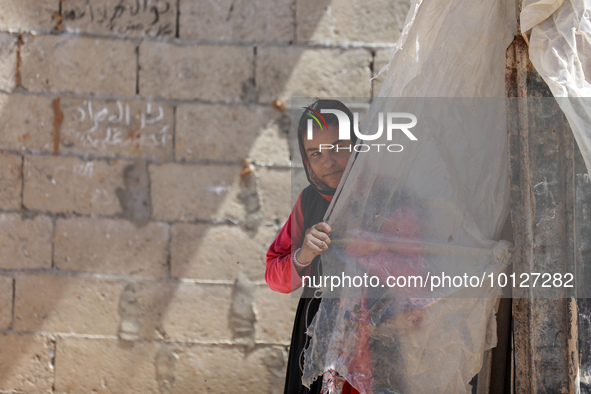 A Palestinian girl looks through plastic sheets outside her home in a poor neighborhood in Beit Lahia in the northern Gaza Strip, on June 5,...