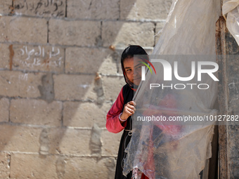 A Palestinian girl looks through plastic sheets outside her home in a poor neighborhood in Beit Lahia in the northern Gaza Strip, on June 5,...