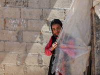 A Palestinian girl looks through plastic sheets outside her home in a poor neighborhood in Beit Lahia in the northern Gaza Strip, on June 5,...
