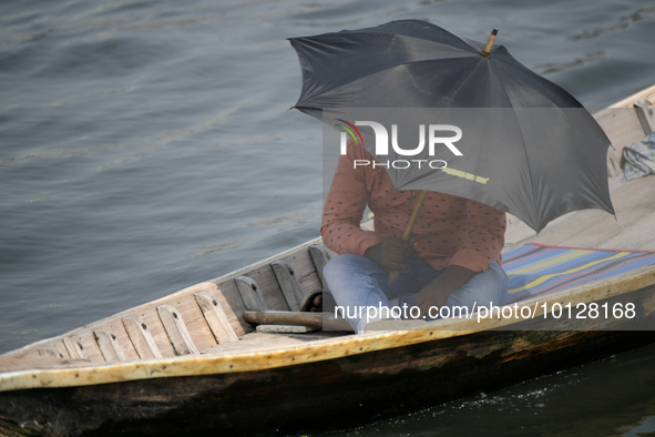 Passengers cross the river Buriganga as they hold an umbrella to prevent suns heat during a heat wave in Dhaka, Bangladesh, May 06, 2023....