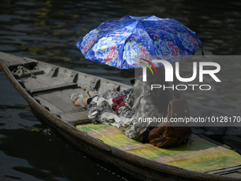 Passengers cross the river Buriganga as they hold an umbrella to prevent suns heat during a heat wave in Dhaka, Bangladesh, May 06, 2023....