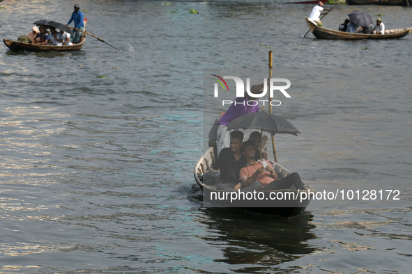 Passengers cross the river Buriganga as they hold an umbrella to prevent suns heat during a heat wave in Dhaka, Bangladesh, May 06, 2023....