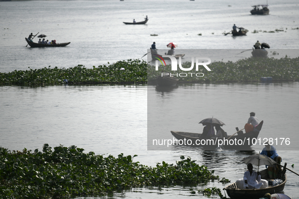 Passengers cross the river Buriganga as they hold an umbrella to prevent suns heat during a heat wave in Dhaka, Bangladesh, May 06, 2023....