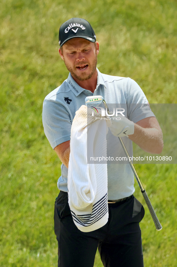 Danny Willett of Sheffield, England cleans off his club after hitting from the bunker on the 17th green during The Memorial Tournament prese...