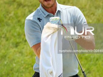 Danny Willett of Sheffield, England cleans off his club after hitting from the bunker on the 17th green during The Memorial Tournament prese...